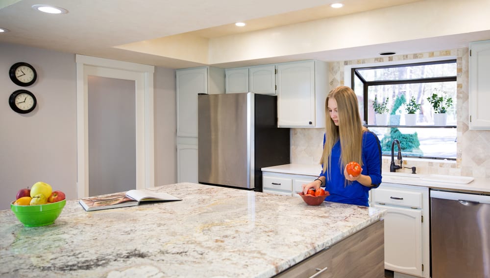 Woman stands with a tomato in her hand in front of quartz kitchen island countertop